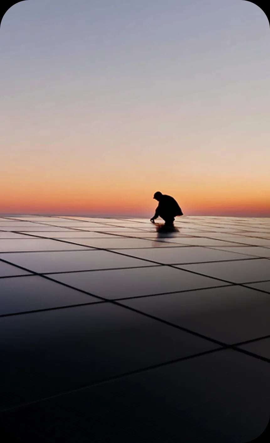 Worker silhouette on solar panels at sunset